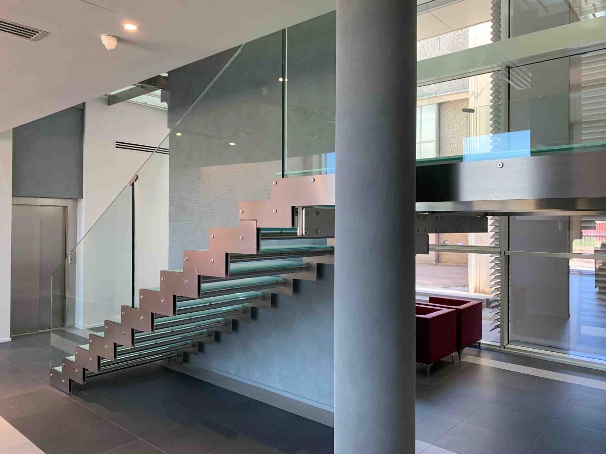 Scala interna in metallo con parapetto e gradini in vetro